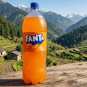Fanta bottle on a wooden table with a scenic mountain landscape in the background