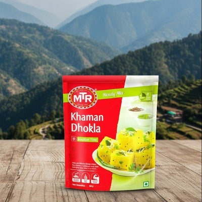 MTR Khaman Dhokla packaging on a wooden surface with a mountainous landscape in the background