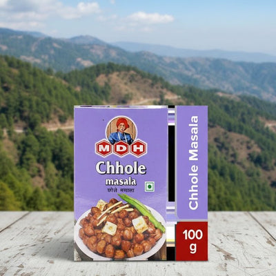 Box of MDH Chhole masala with a mountainous landscape in the background