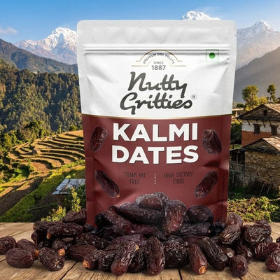 Bag of Nutty Gritties Kalmi Dates with a scenic background of mountains and terraced fields.