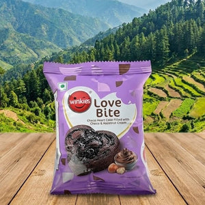 Winkies Love Bite chocolate bar packaging on a wooden surface with a scenic mountain background