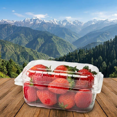 Container of strawberries on a wooden table with a mountainous landscape in the background