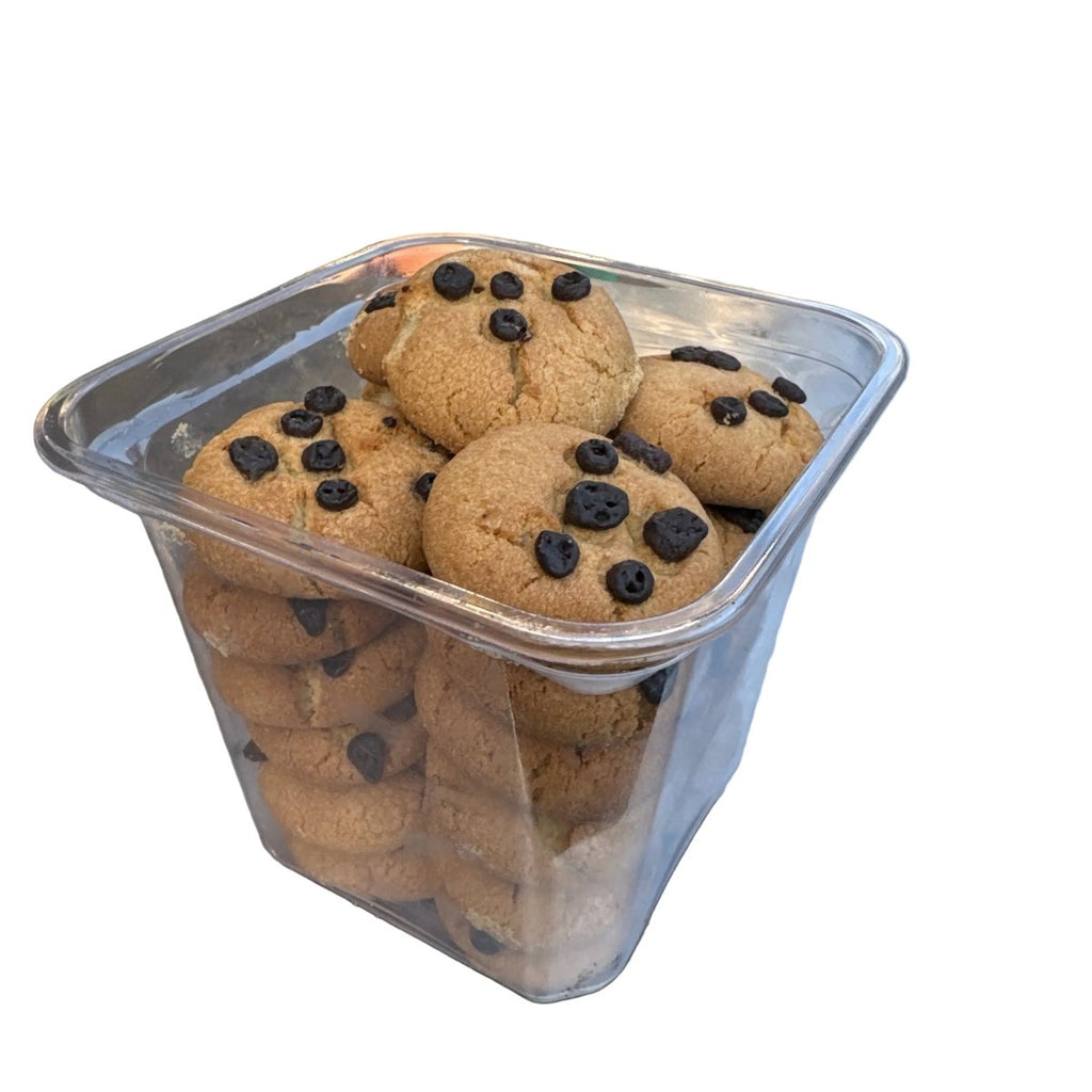 Container of cookies with chocolate chips on a metal surface