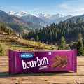 Cremica bourbon chocolate bar on a wooden surface with a mountainous landscape in the background