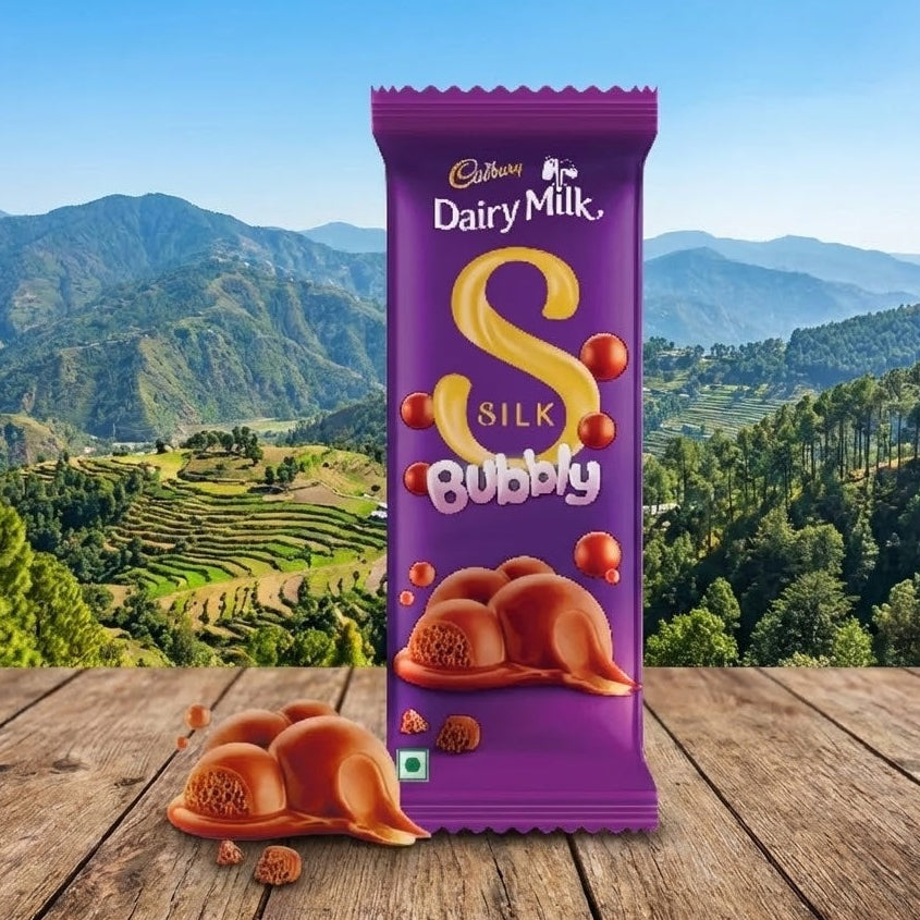 Cadbury Dairy Milk Silk Bubbly chocolate bar with a scenic background of mountains and trees.