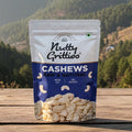 Bag of Nutty Gritties Cashews on a wooden surface with a mountainous landscape in the background