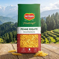 Del Monte Penne Rigate pasta package on a wooden table with a scenic mountain background