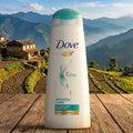 Dove dryness care shampoo bottle on a wooden surface with a mountainous landscape in the background