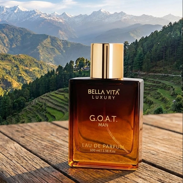 Bella Vita Luxury G.O.A.T. Man perfume bottle on a wooden table with a mountainous landscape in the background