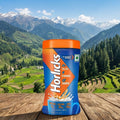 Horlicks container on a wooden surface with a scenic mountain background