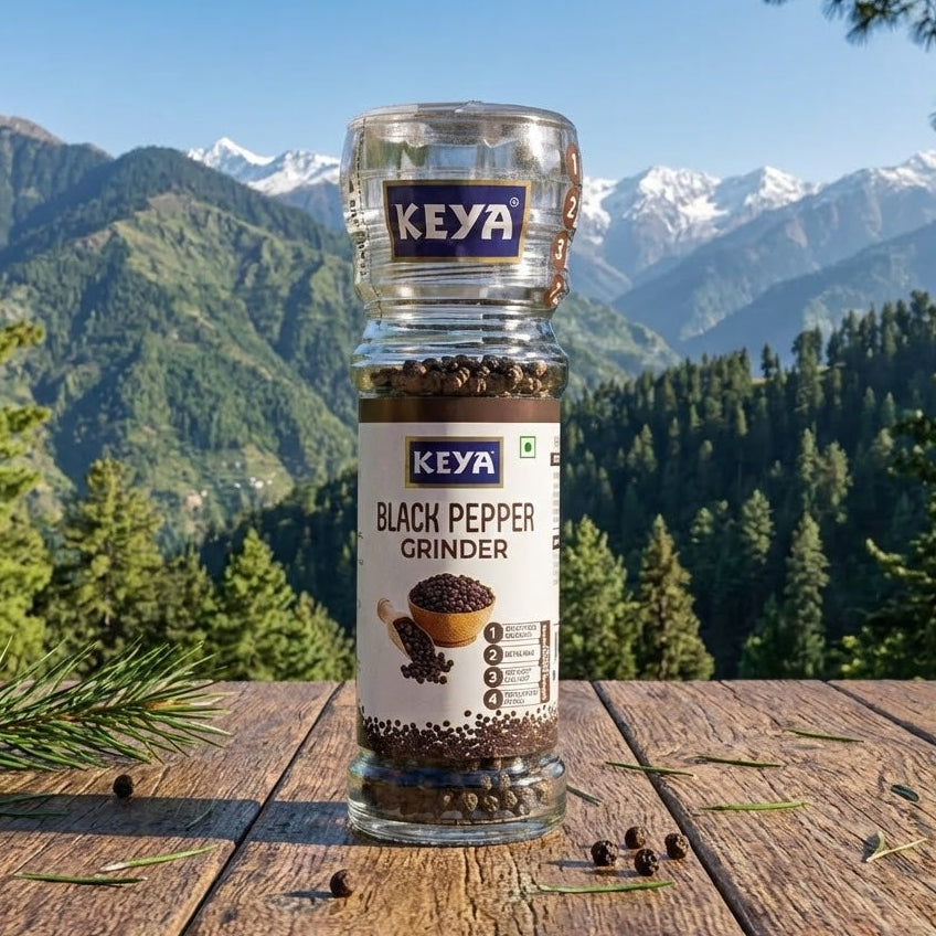 KEYA black pepper grinder on a wooden surface with a mountainous landscape in the background