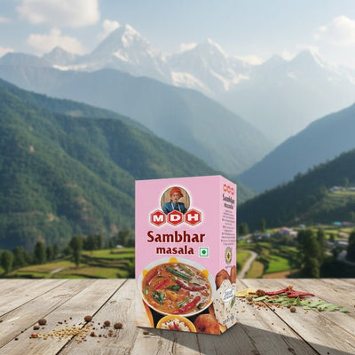 Box of MDH Sambhar masala on a wooden surface with a mountainous landscape in the background