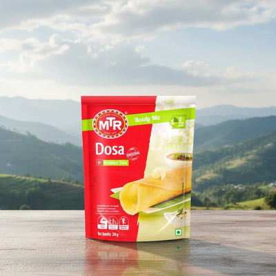MTR Dosa package on a wooden surface with a mountainous landscape in the background