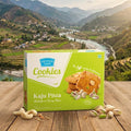 Box of Kaju Pista cookies with a scenic mountain landscape in the background