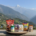 Assorted snacks on a wooden tray with a mountainous landscape in the background