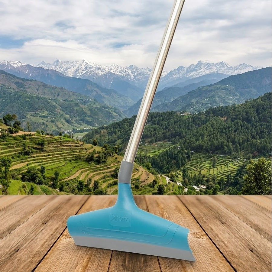 Blue squeegee on a wooden surface with a scenic mountain landscape in the background