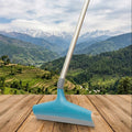 Blue squeegee on a wooden surface with a scenic mountain landscape in the background