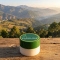 Jar of Boroline cream on a wooden surface with a scenic mountain landscape in the background