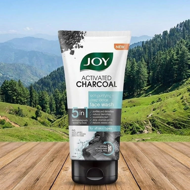 Joy Activated Charcoal face wash tube on a wooden surface with a scenic background