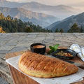Loaf of bread on a wooden table with a scenic mountain view in the background