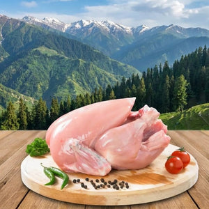Raw chicken on a wooden cutting board with vegetables against a mountainous landscape