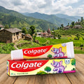 Colgate toothpaste packaging with a scenic background of mountains and village.