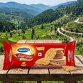 Cremica Digestive cookies package on a wooden table with a scenic mountain landscape in the background