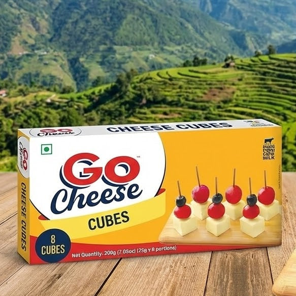 Go Cheese Cubes packaging with cheese cubes on a wooden board against a mountainous landscape.