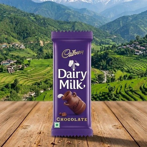 Cadbury Dairy Milk chocolate bar on a wooden surface with a scenic mountain landscape in the background