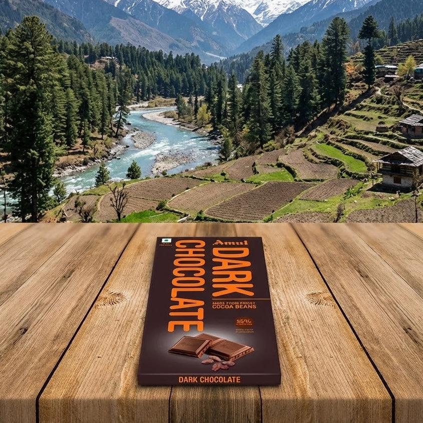 Chocolate bar packaging on a wooden surface with a scenic mountain landscape in the background