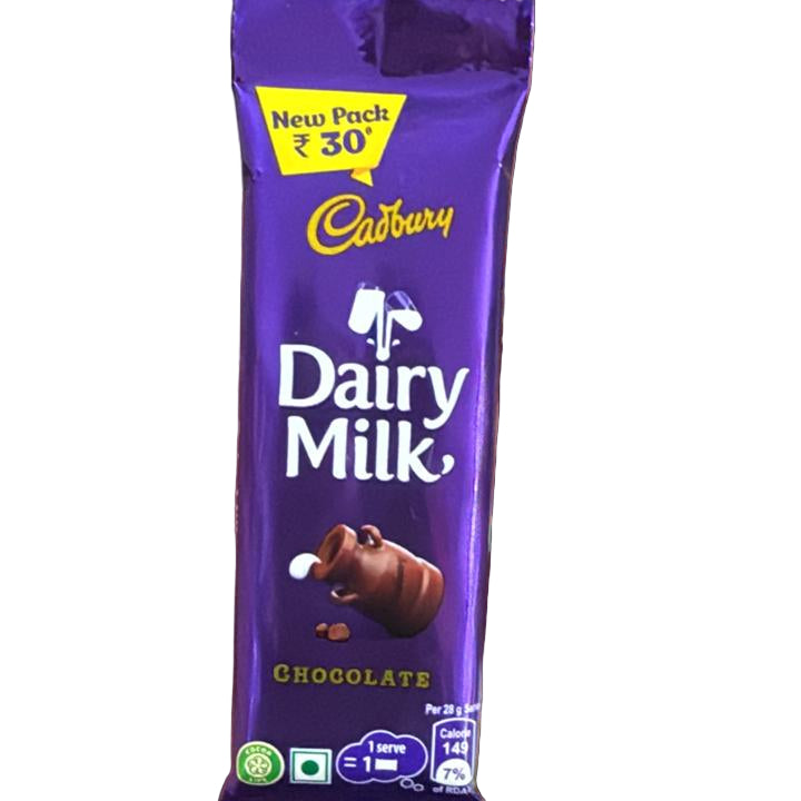 Hand holding a Cadbury Dairy Milk chocolate bar with colorful snacks in the background