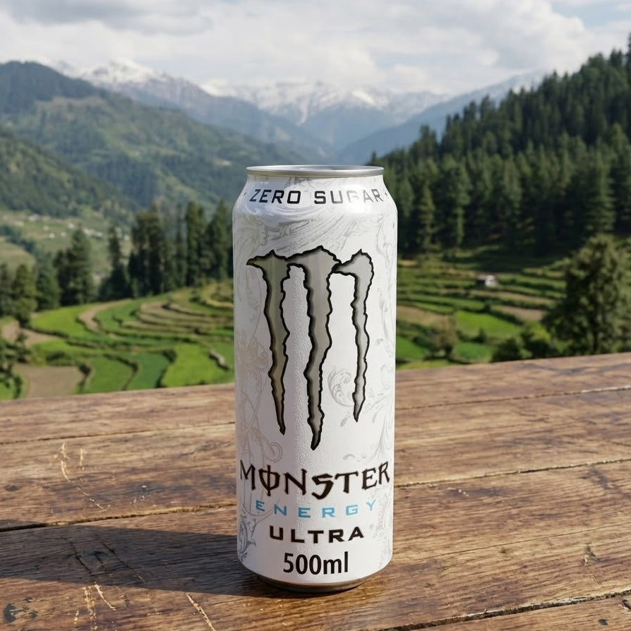 Monster Energy Ultra can on a wooden surface with a scenic background of mountains and trees.