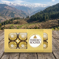 Ferrero Rocher chocolate box on a wooden surface with a mountainous landscape in the background