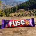 Cadbury Fuse chocolate bar on a wooden surface with a mountainous landscape in the background