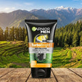 Garnier Men TurboBright foam tube on a wooden surface with a scenic mountain background