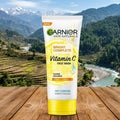 Garnier Skin Naturals Vitamin C Face Wash tube on a wooden surface with a mountainous landscape in the background