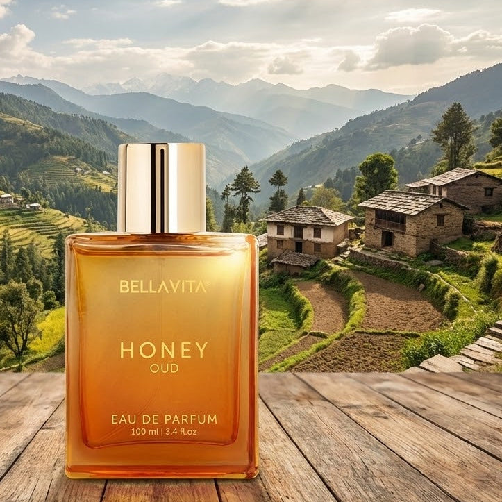Bellavita Honey Oud perfume bottle on a wooden surface with a scenic mountain landscape in the background