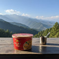 Red instant noodles cup with a spoon on a wooden table against a mountainous landscape