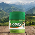 IODEX container on a wooden surface with a mountainous landscape in the background