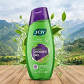 Green bottle of JOY shower gel with a mountainous landscape in the background