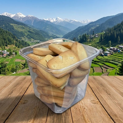 Clear container of cookies on a wooden surface with a mountainous landscape in the background