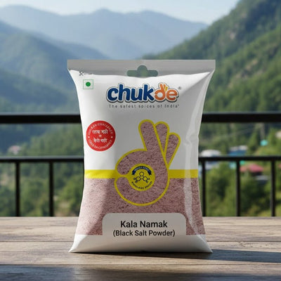 Bag of chukde Kala Namak black salt powder with a mountainous landscape in the background