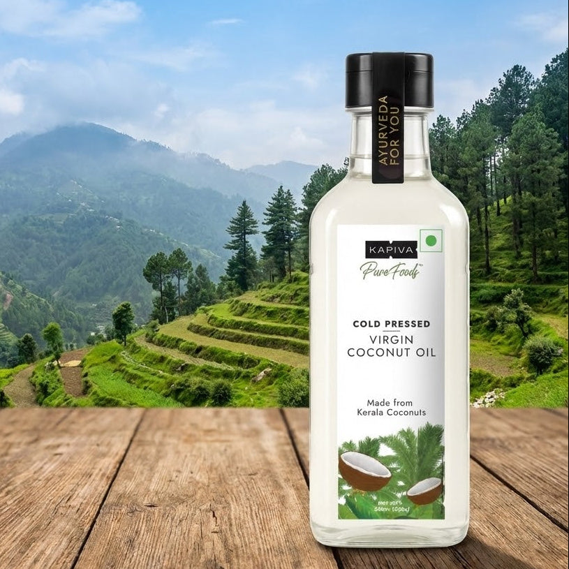 Bottle of Kapiva Virgin Coconut Oil on a wooden surface with a scenic mountain background