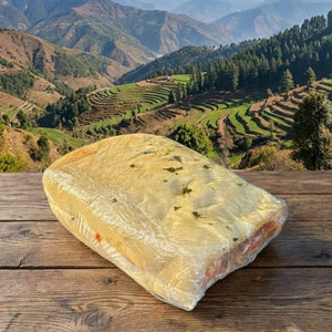 Loaf of bread on a wooden table with a scenic mountain landscape in the background