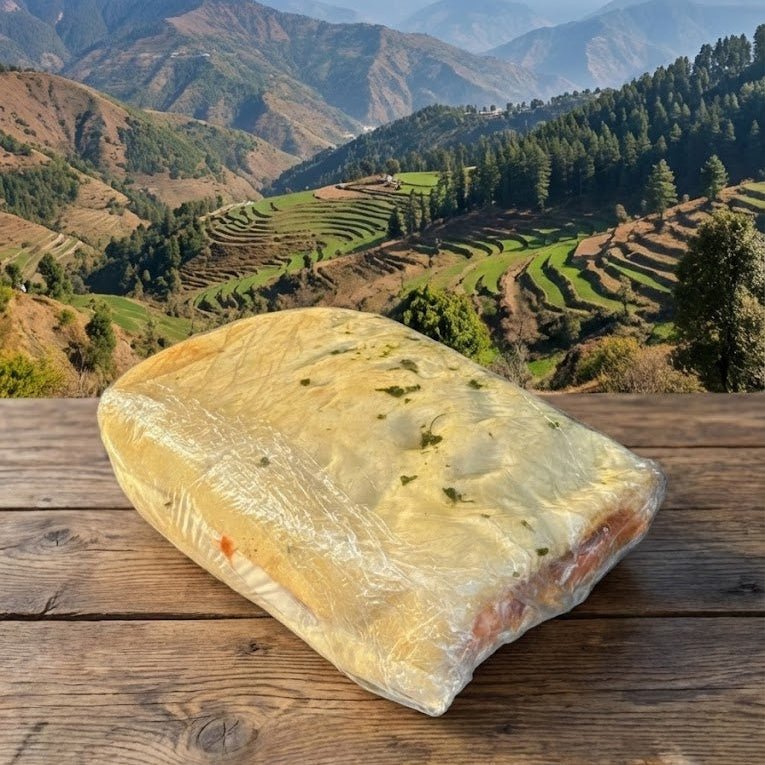 Loaf of bread on a wooden table with a scenic mountain landscape in the background