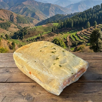 Loaf of bread on a wooden table with a scenic mountain landscape in the background