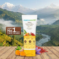 Mamaearth Ubtan Natural Glow Face Wash with a scenic background of mountains and river.