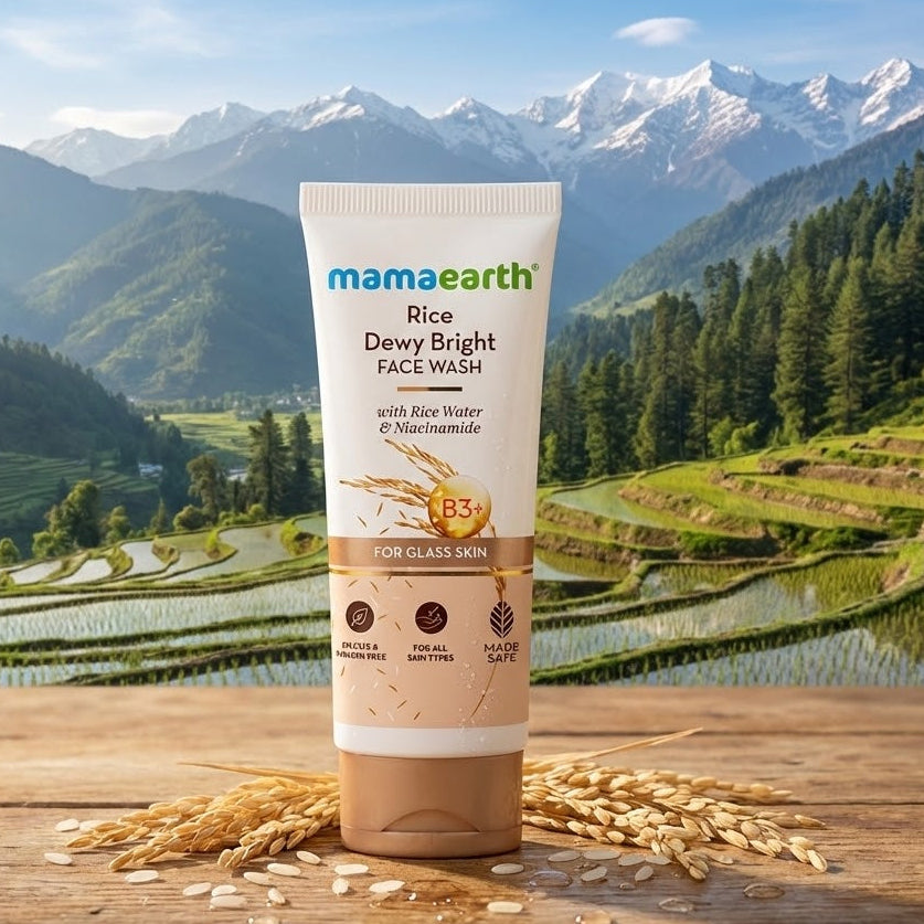 Mamaearth Rice Dewy Bright Face Wash tube with a scenic background of mountains and fields.