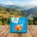 Packaged milk rusk on a wooden surface with a scenic mountain background
