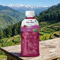 Pink bottle of Mogõ Mogõ on a wooden table with a scenic mountain background